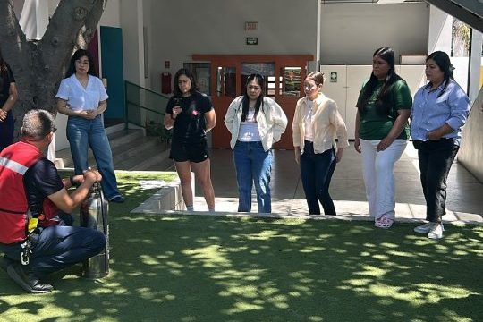 Padres y madres de familia reunidos en el patio de Reguilete durante una junta de inicio de ciclo