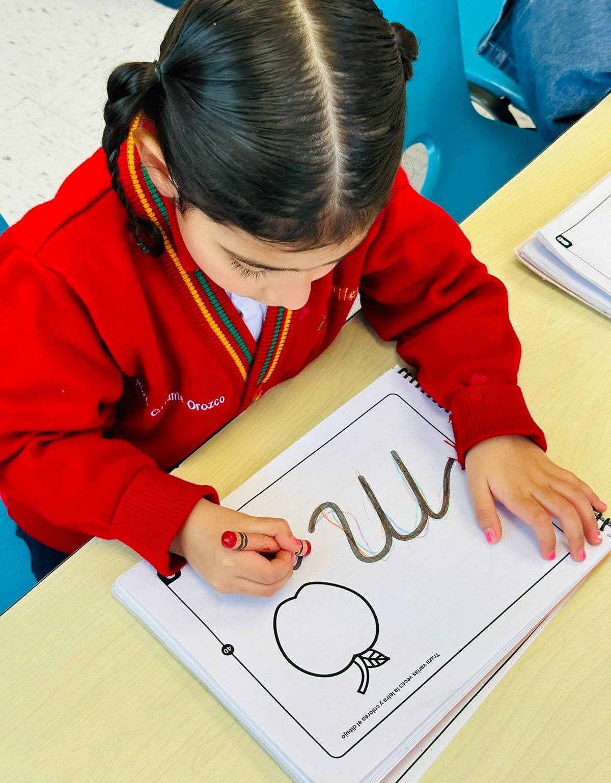 Niña de preescolar trazando líneas en su cuaderno de lectoescritura